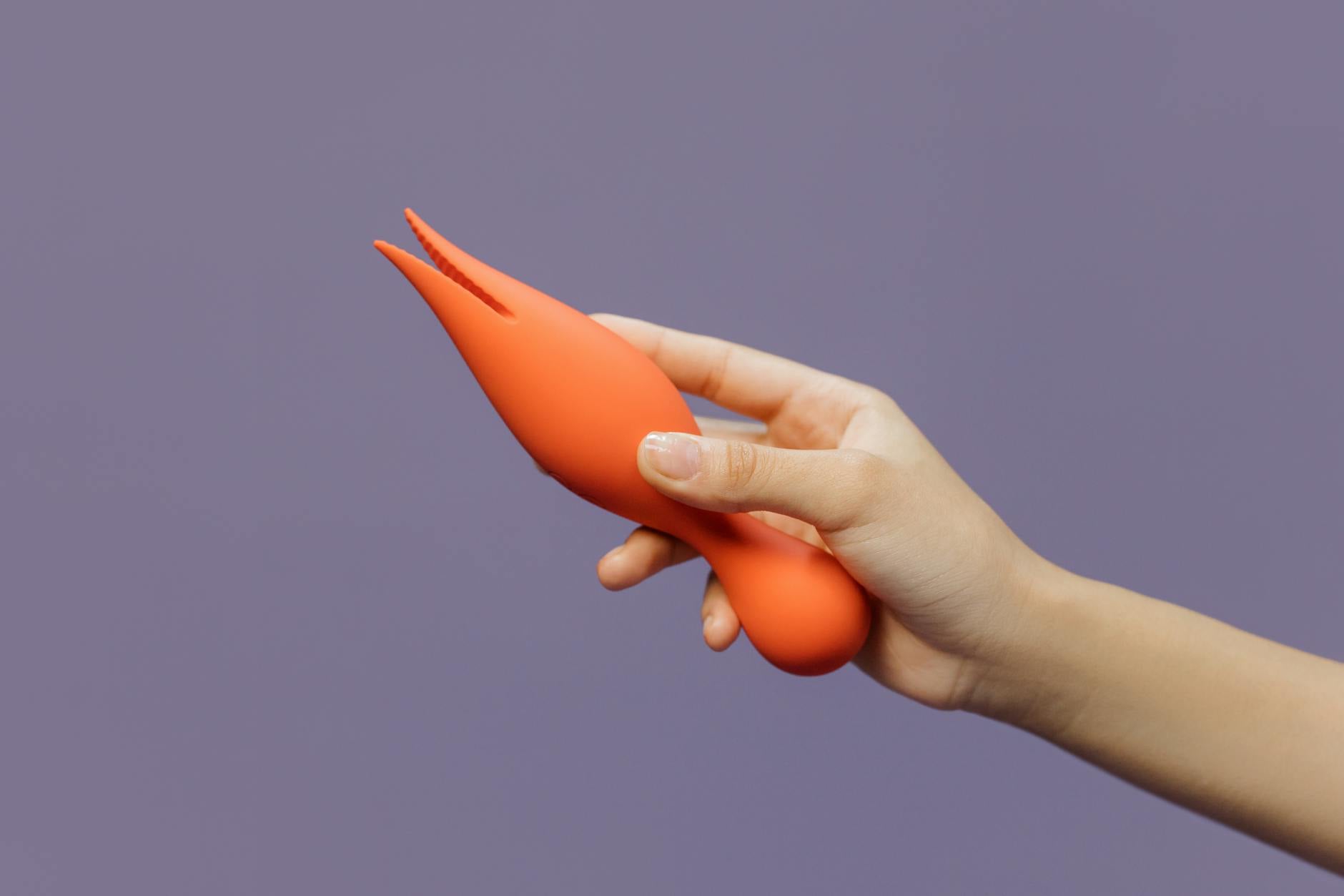 Hand holding a lemon vibrator against a minimalistic purple backdrop, showcasing modern sensuality and self-care.