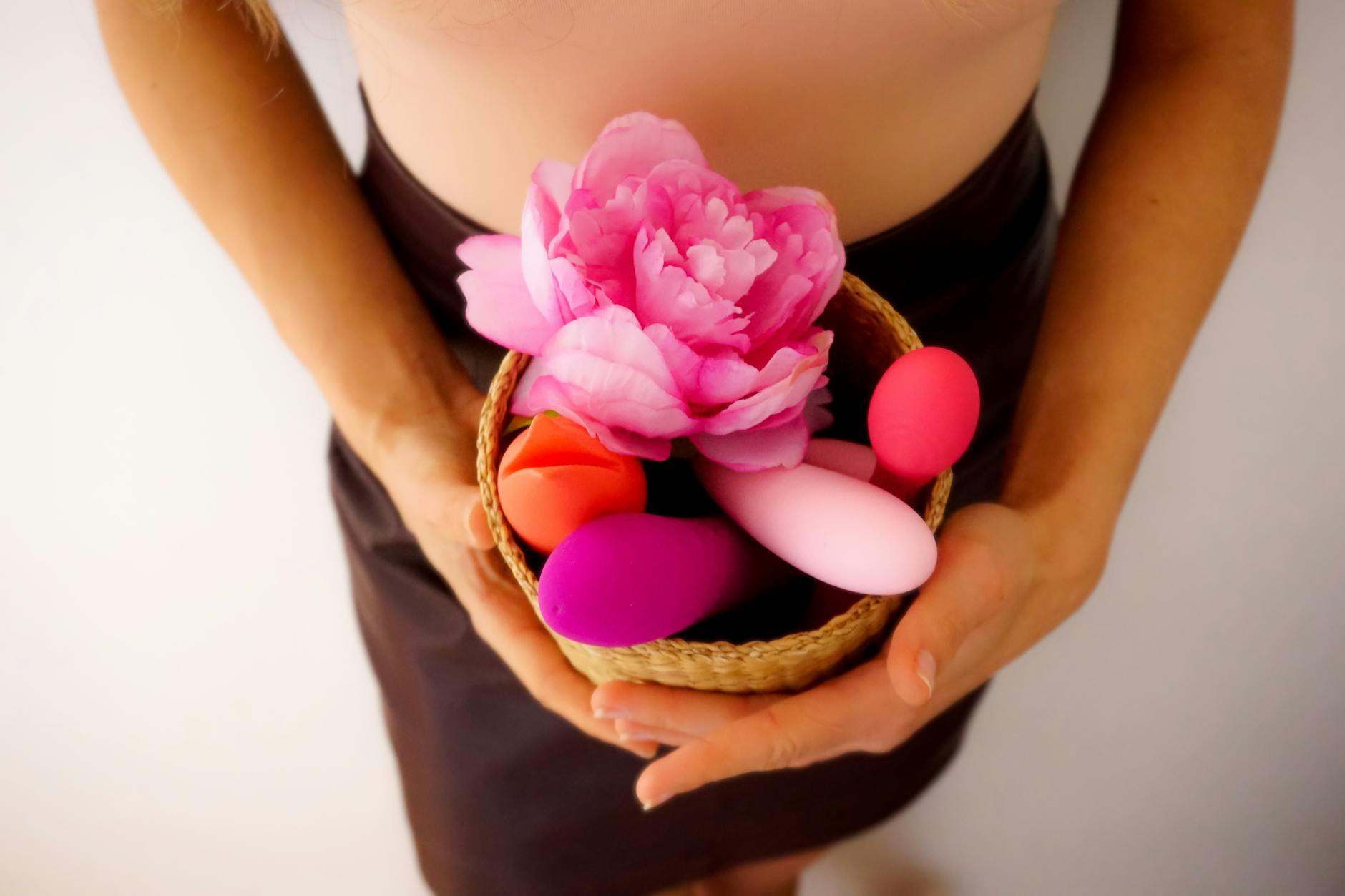 Woman holding vibrators thoughtfully, representing the vulnerability of intimate moments with a partner present